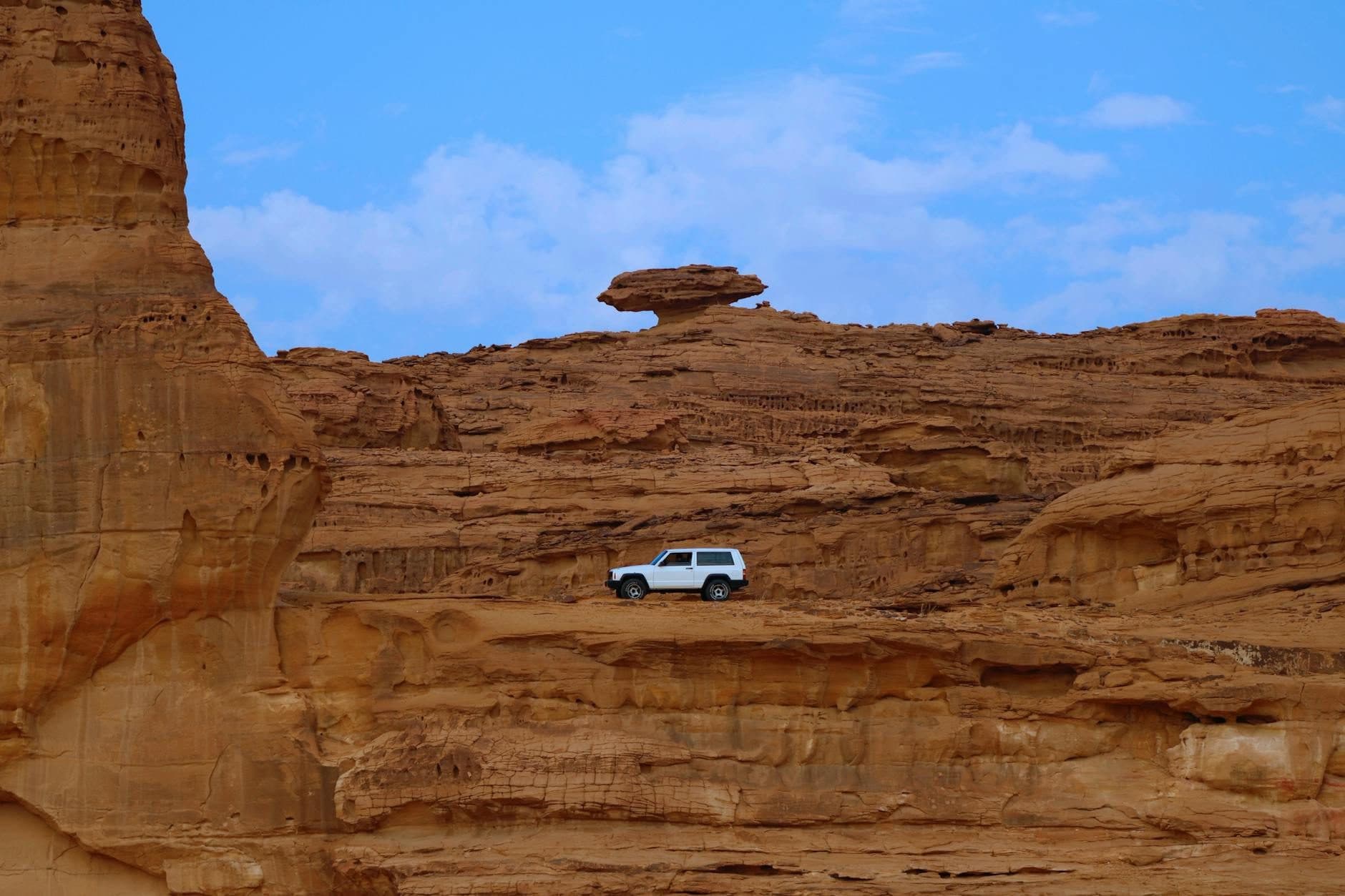 Sandstone cliffs in the AlUla valley, with a vehicle for scale